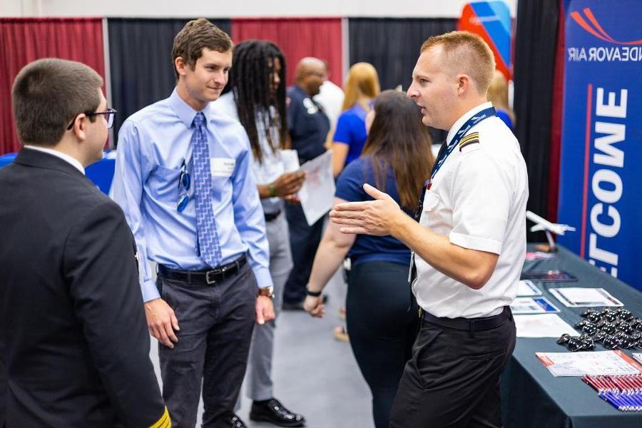 A pilot speaks with students at a career fair